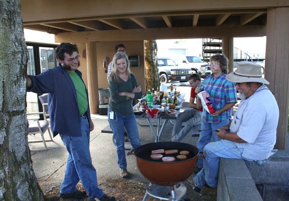 Entomology program staff gather around a charcoal grill during a summer BBQ.