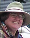 Smiling woman in glasses and a broad-brimmed hat.